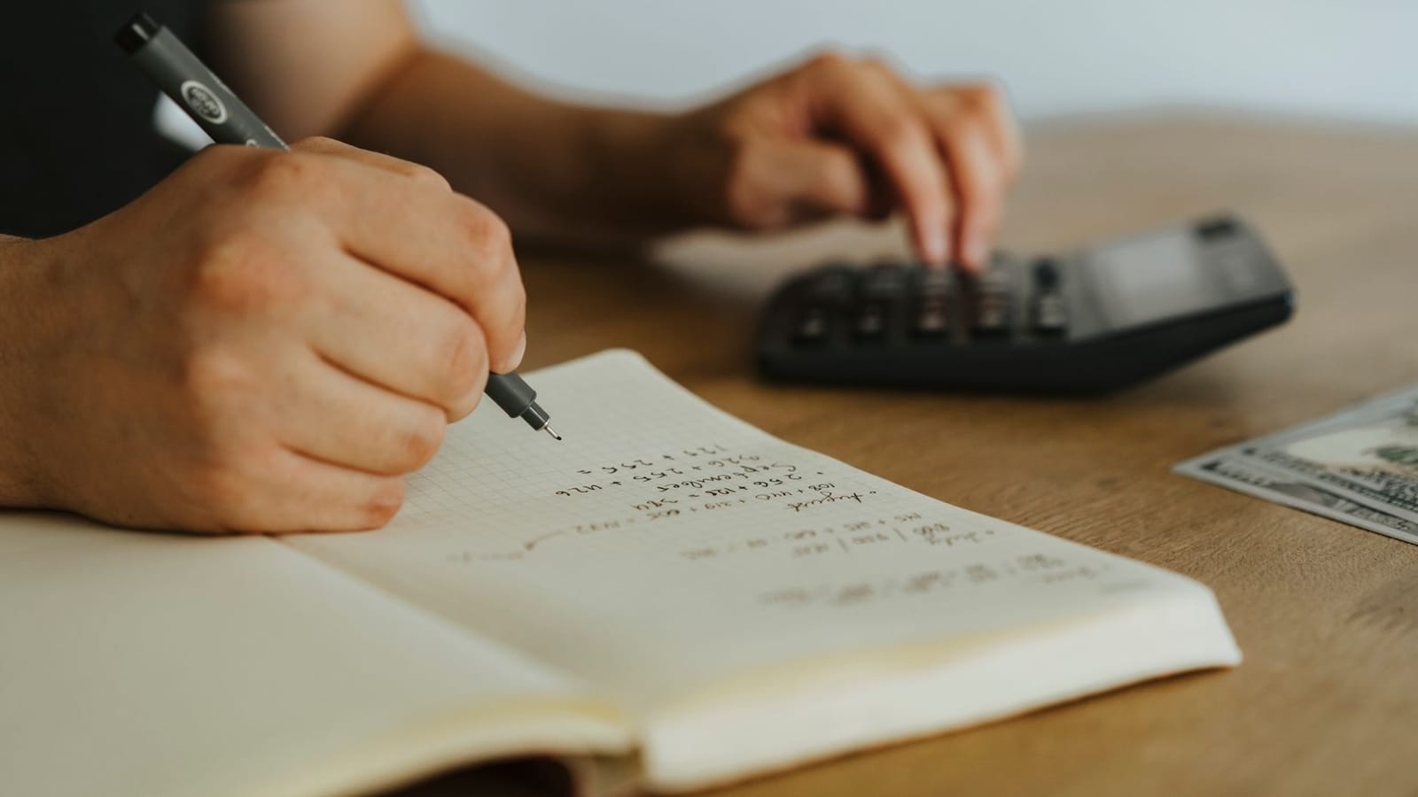 Unes mans que anoten números en una llibreta quadriculada mentre fan servir una calculadora